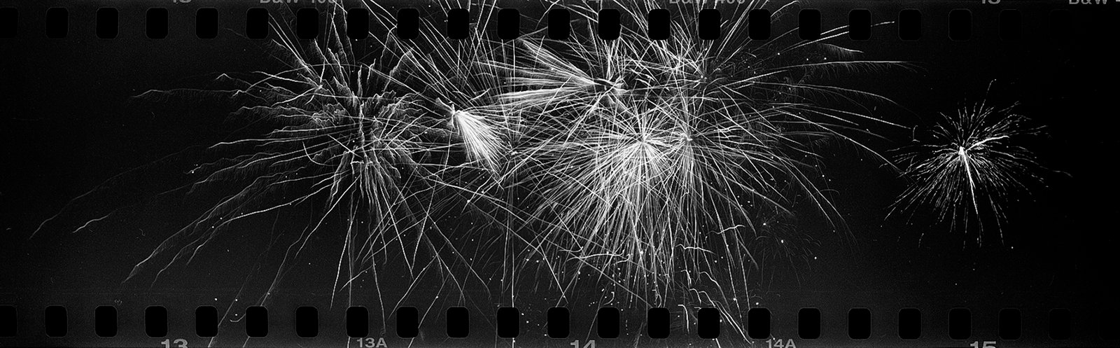 Within the borders of an old film strip is a high definition photo of fireworks.